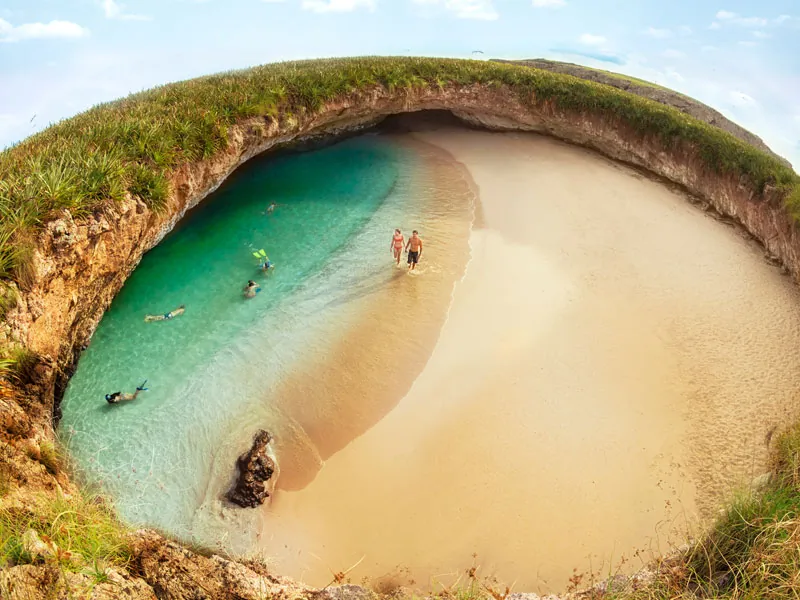Aerial view of the hidden beach at the Marietas Islands, with snorkelers in the turquoise water inside the crater