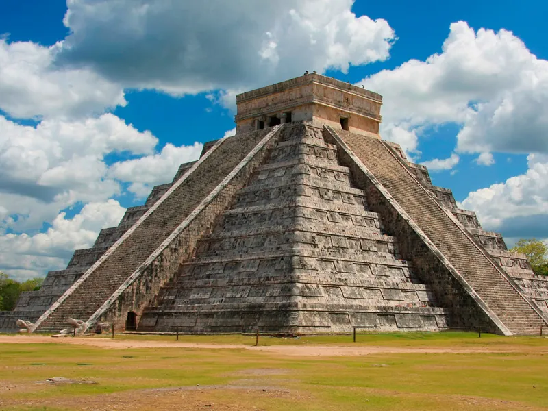 The Pyramid of Kukulcán at Chichén Itzá under white clouds and a deep blue sky
