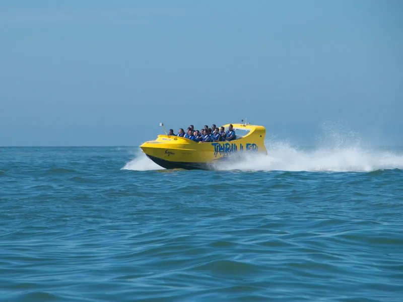 Yellow Thriller jet boat full of passengers skimming across open water