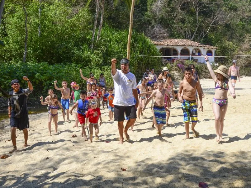Children and pirate crew racing across the sand at Majahuitas beach