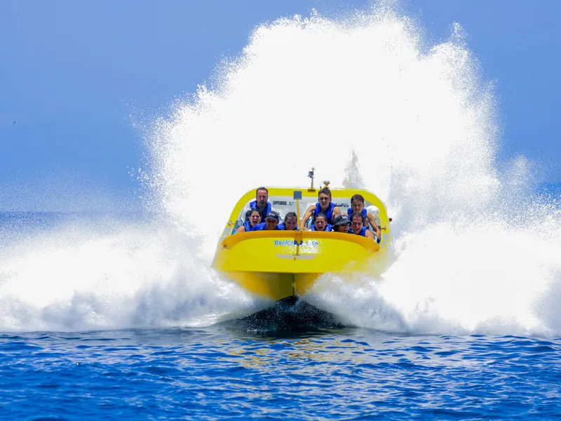 Jet boat charging head-on through a wall of white spray on the bay