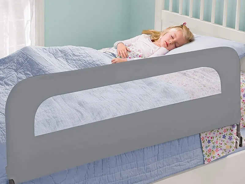 Toddler asleep in a bed fitted with a safety rail