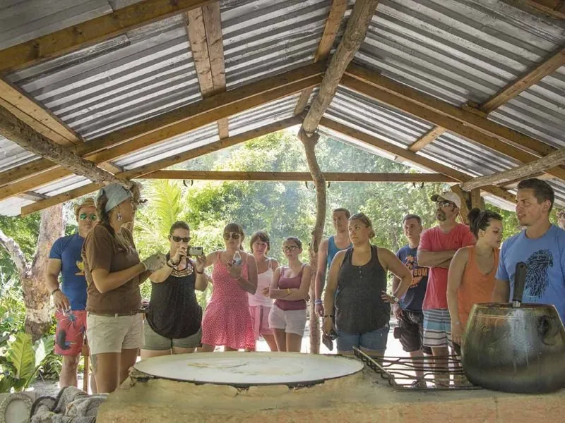 Group of guests gathered around a large comal under a tin-roofed palapa