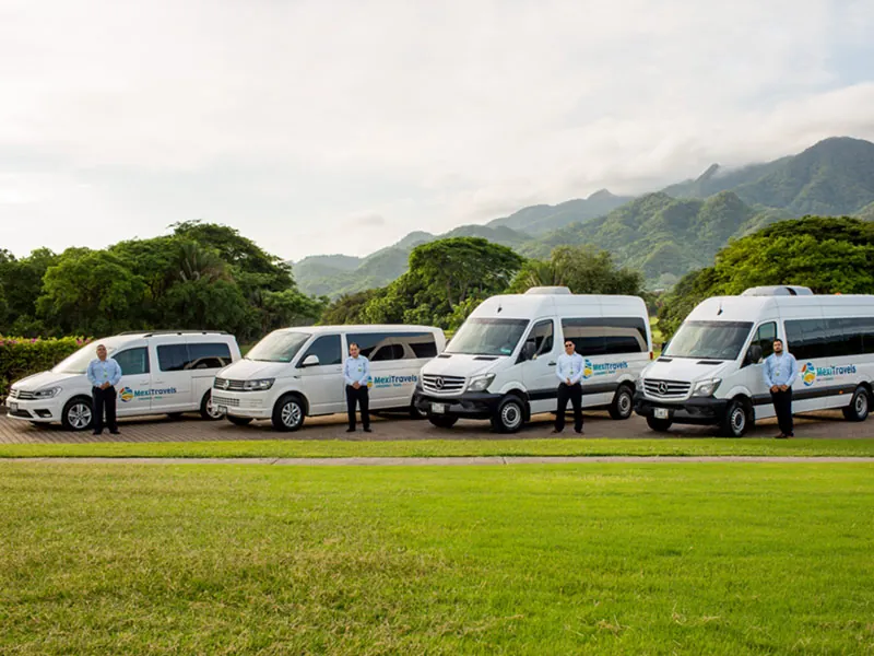 Line of white transfer vans parked on a lawn with the Sierra Madre behind