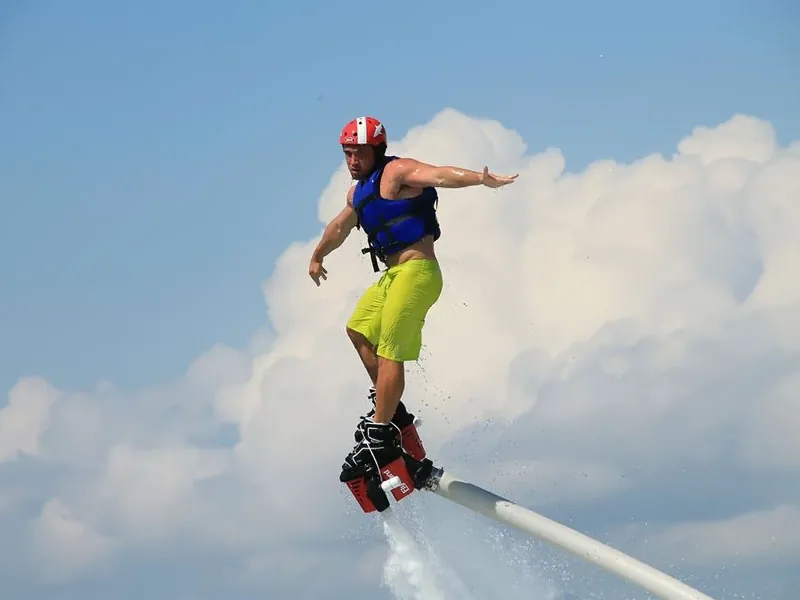 Flyboarder leaning into a turn against white clouds