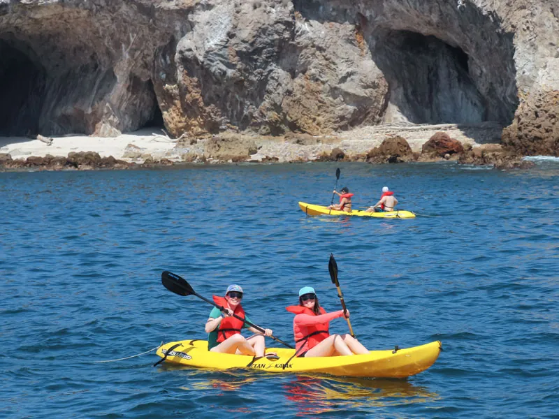 Two guests kayaking beside volcanic rock arches