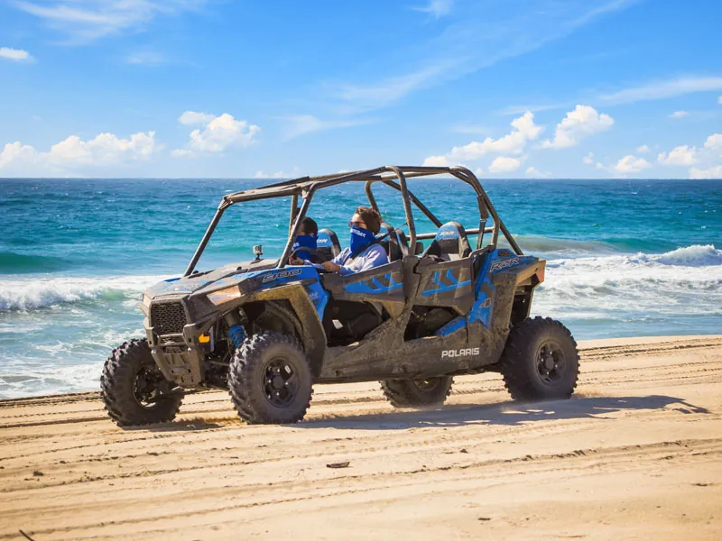 Polaris UTV parked on a beach with the Pacific surf behind