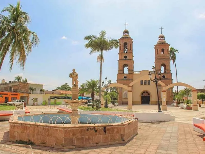 Twin-towered village church with a fountain and palms in the square