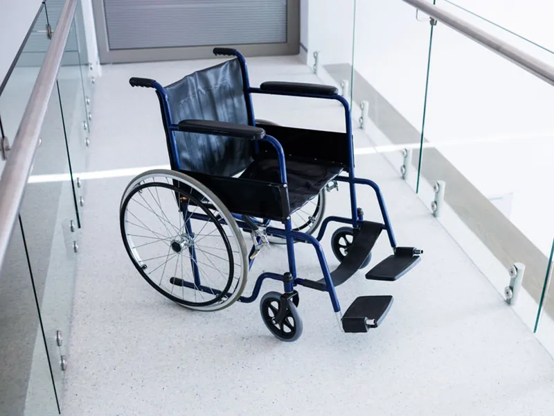 Folding wheelchair with black seat in a bright hallway