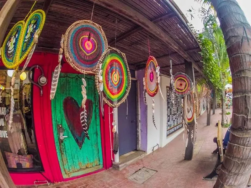 Colorful Huichol yarn mandalas hanging outside a shop with a painted door in Sayulita