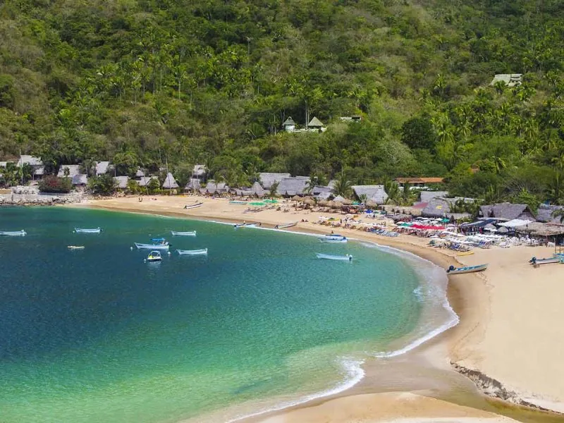 Curved beach and bay at Yelapa seen from above, pangas moored off the sand and jungle hills behind